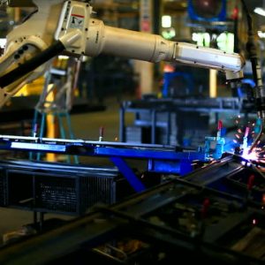 Robot arm welding uses torch to make sparks during manufacture of metal equipment.